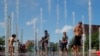 FILE - Kids and adults cool off in a fountain on the Rose Kennedy Greenway on the first day of a forecasted summer heatwave in Boston, Massachusetts, July 19, 2019. Some people hope summer will slow the spread of COVID-19.